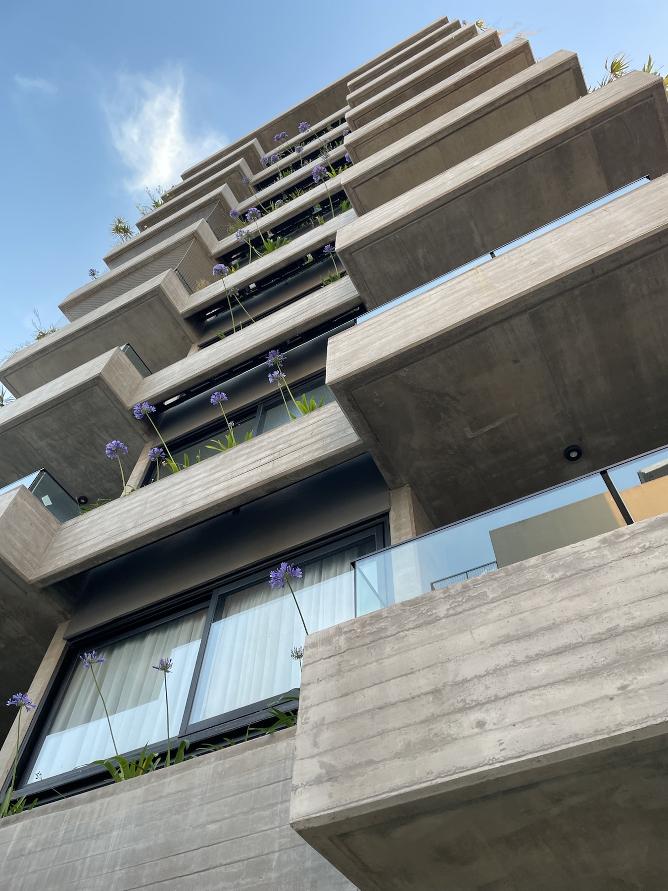 Fachada construida de Beton Garden con balcones de hormigón y vegetación