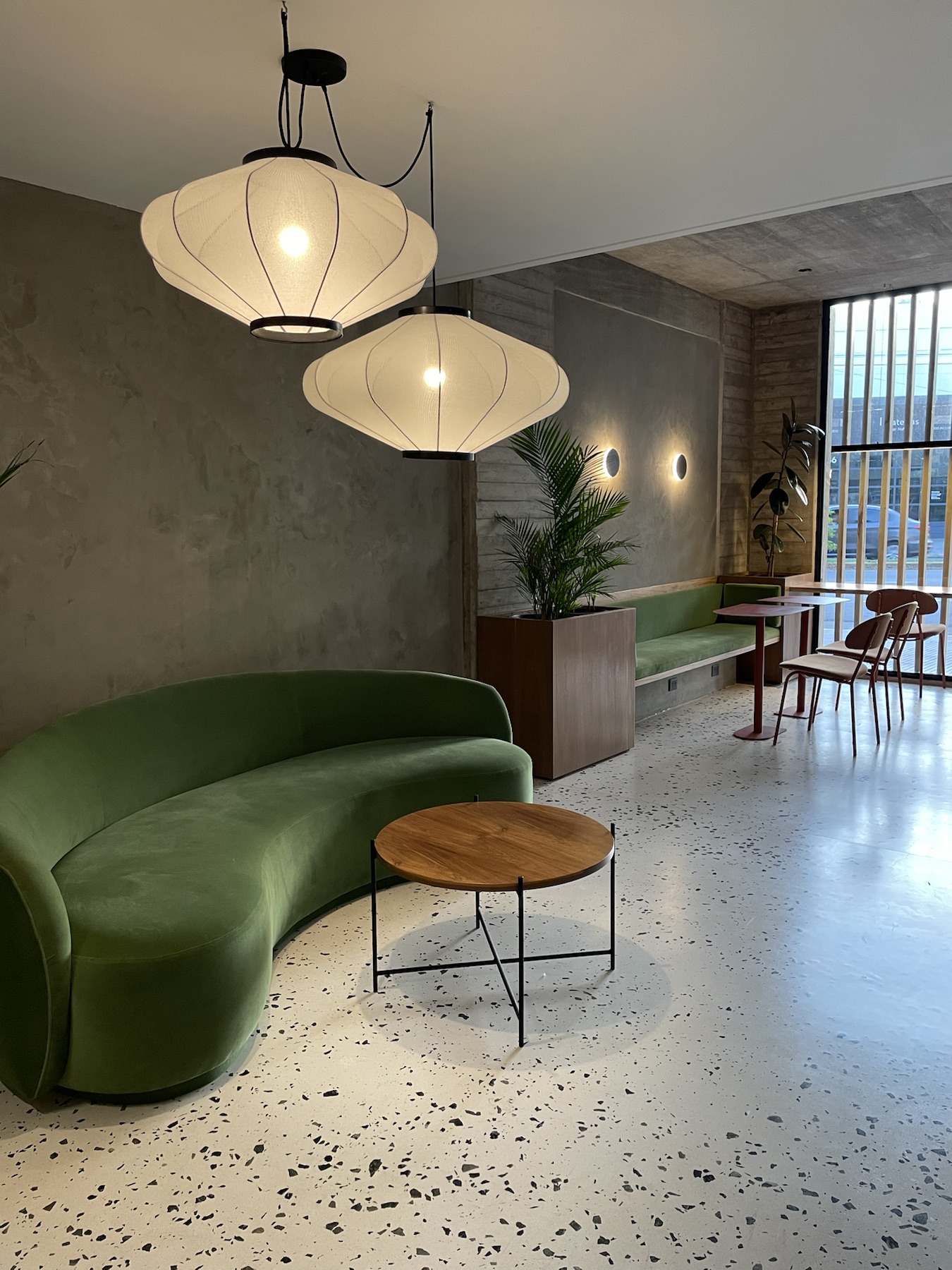 Sector de estar del SUM con mobiliario verde e iluminación colgante