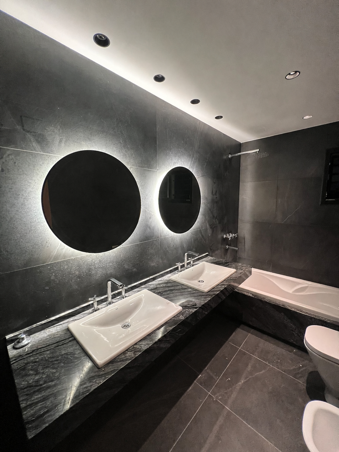 Baño con espejos circulares retroiluminados