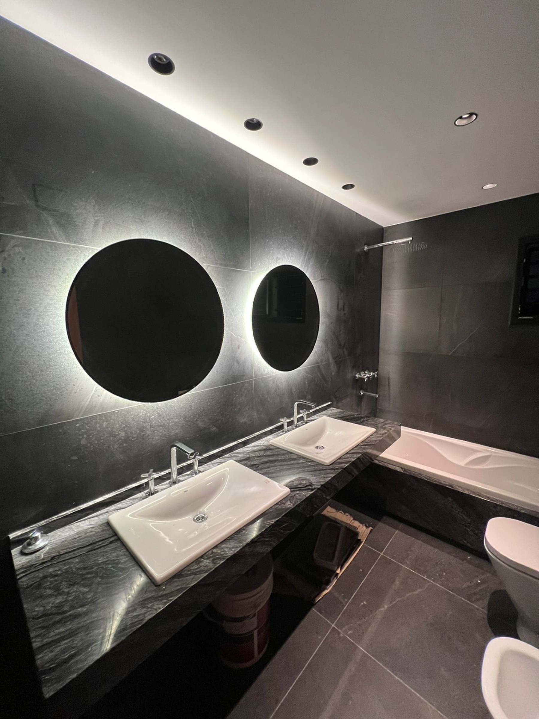 Baño con espejos circulares retroiluminados